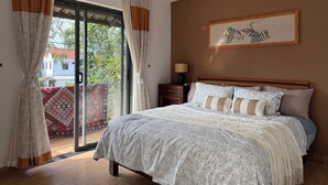 A bedroom with a large bed, a nightstand, a lamp, and a window with curtains. - An Bang Antique Beach House (Đà Nẵng)