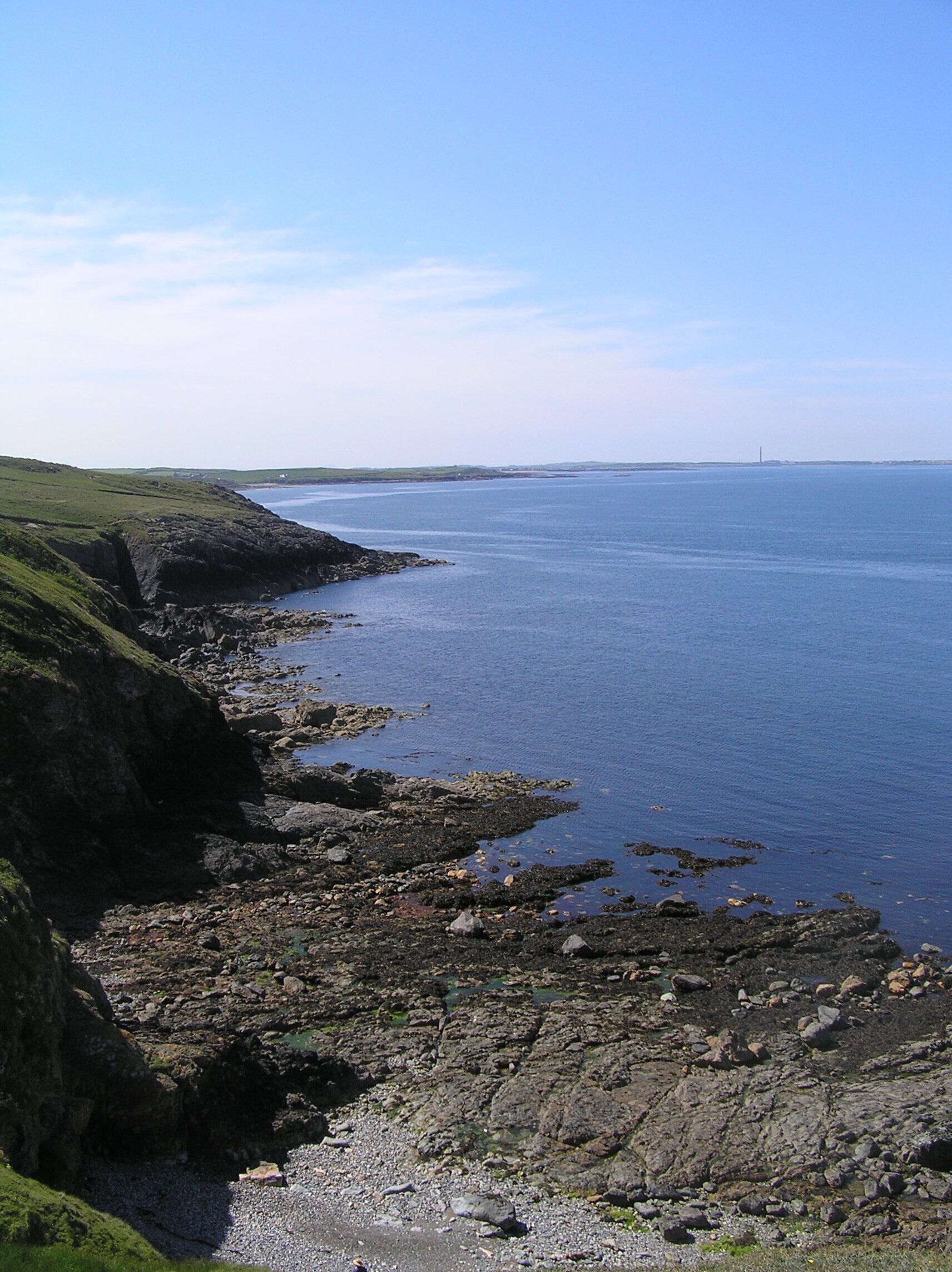 A coastal landscape with rocky terrain and a clear view of the sea.