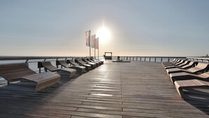 Una terraza de madera con bancos y banderas, con vista a un cuerpo de agua.