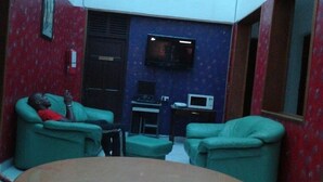 A room with a round table, two green armchairs, a television, and a computer. - Kisiwa Boutique Hotel Mombasa (Mombasa)
