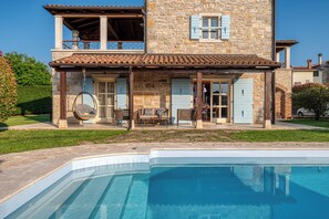 A stone building with a pool, outdoor seating, and a hanging chair. - Historic Istrian Villa: Private Pool, Breakfast & Hot Tub (Višnjan)