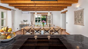 Een eetruimte met een houten tafel, stoelen en een zwart marmeren aanrechtblad.