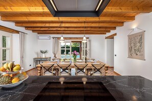 A dining area with a wooden table, chairs, and a black marble countertop. - Historic Istrian Villa: Private Pool, Breakfast & Hot Tub (Višnjan)