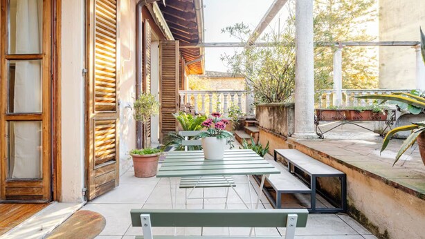 An outdoor patio with a wooden door, a table with chairs, and potted plants. - Terrazze Di Cesy (Brescia)