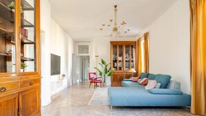 A spacious living room with a blue sofa, wooden cabinet, and a chandelier. - Terrazze Di Cesy (Brescia)