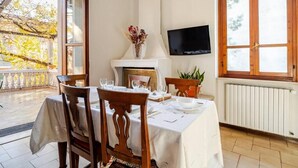 A dining area with a table set for two, a fireplace, a television, and a view of the outdoors. - Terrazze Di Cesy (Brescia)