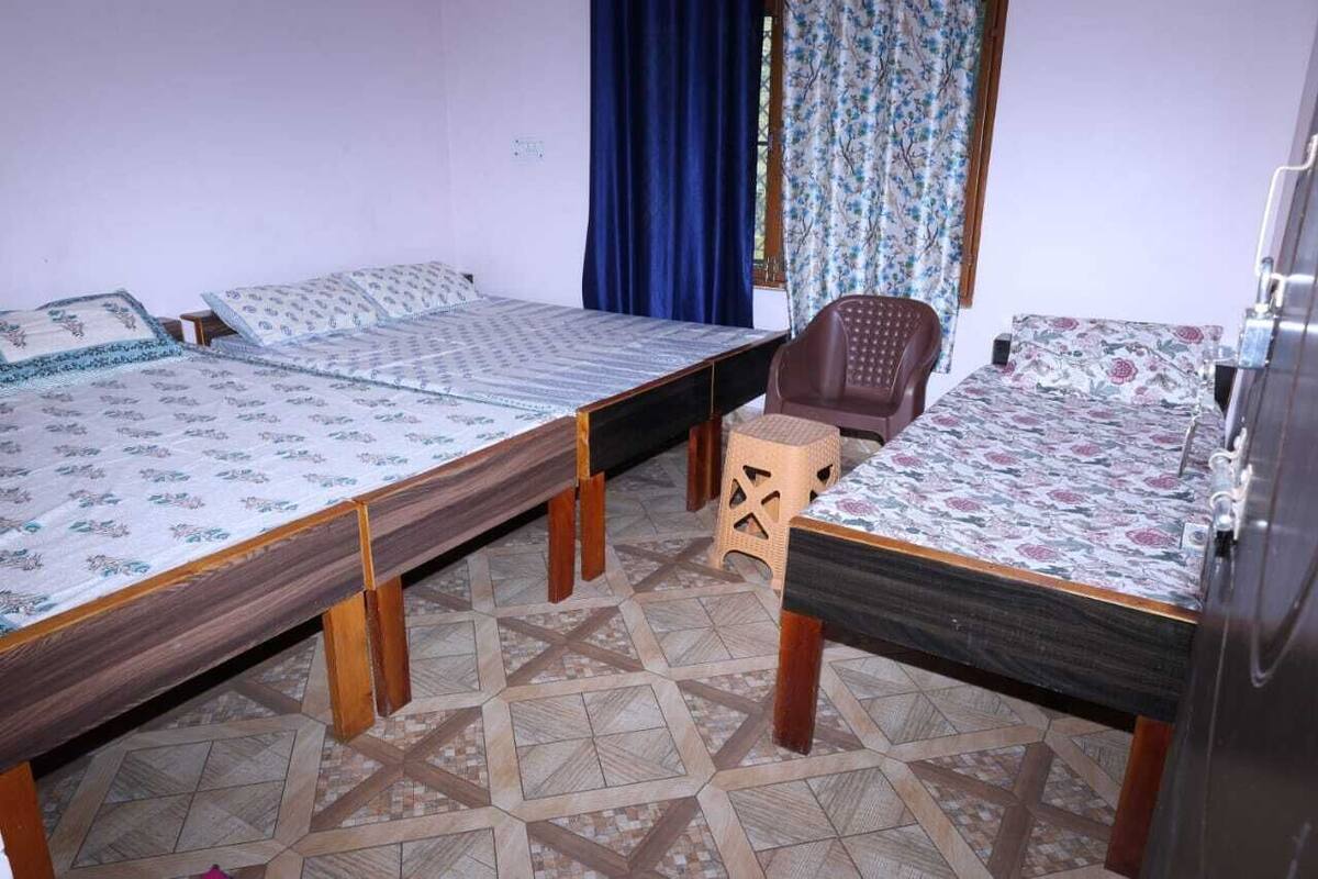 A room with three beds, a chair, and a wardrobe.