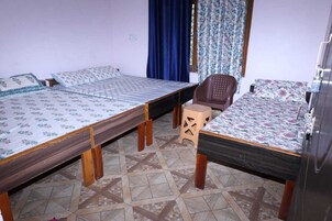 A room with three beds, a chair, and a wardrobe.