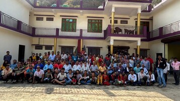 A group of people gathered in an outdoor courtyard with a multi-story building in the background.