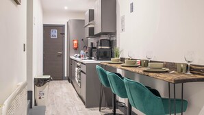 Una cocina moderna con una isla central, taburetes de bar y un microondas.