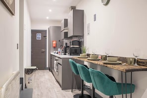 Een moderne keuken met een centraal eiland, barkrukken en een magnetron.