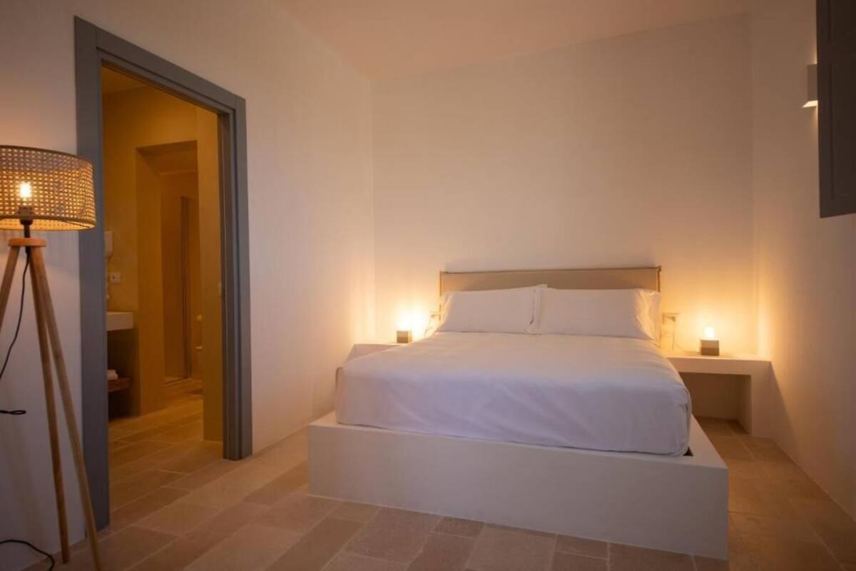 A bedroom with a bed, bedside lamps, and a door leading to a bathroom.
