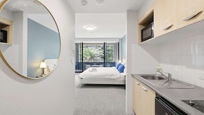 A modern hotel room with a bed, a bathroom, and a kitchen area. - MetaWiseBnB |Cronulla Beach Walk to Train & Shops1 (Cronulla)