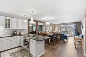 A modern kitchen with white cabinets, a central island, and pendant lighting. - Twin Lakes Getaway (Branson)