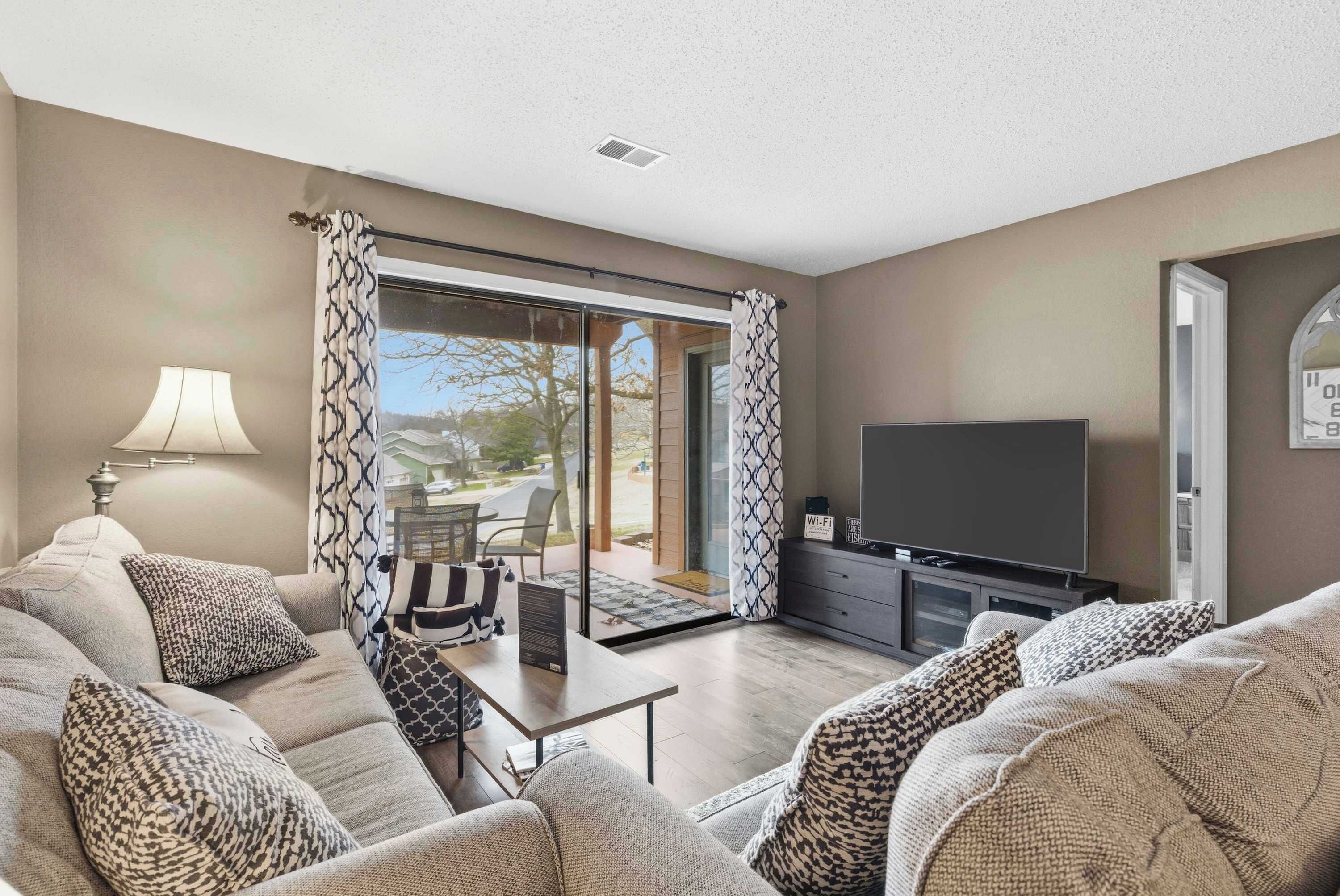 A living room with a sofa set, a TV, a lamp, and a dining area with a table and chairs.
