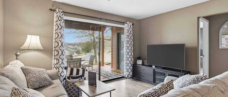 A living room with a sofa set, a TV, a lamp, and a dining area with a table and chairs.