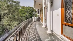 Un balcon doté d’une balustrade incurvée donnant sur un espace verdoyant luxuriant.