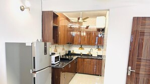 Une cuisine de taille réduite, avec des meubles en bois, un réfrigérateur blanc, un four à micro-ondes et un évier.