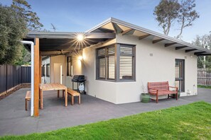 A modern house with a covered patio, a wooden bench, and a grill. - Beachside Escape | 100m to Beach | Walk to Cafés (Cowes)