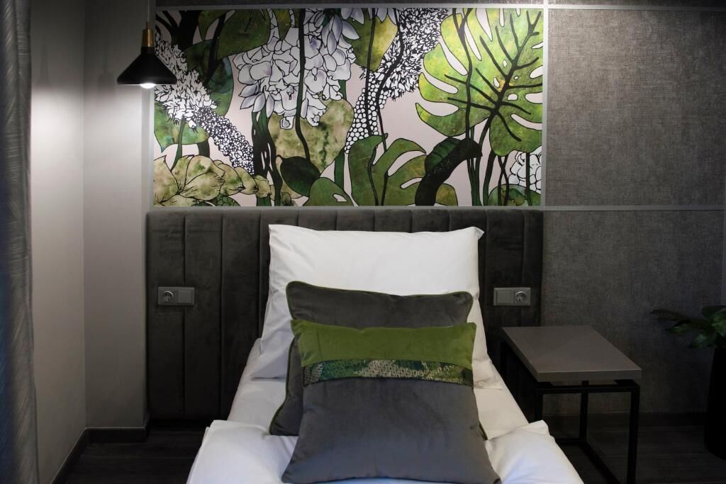 A bedroom with a bed, a nightstand, a lamp, and a wall mural.