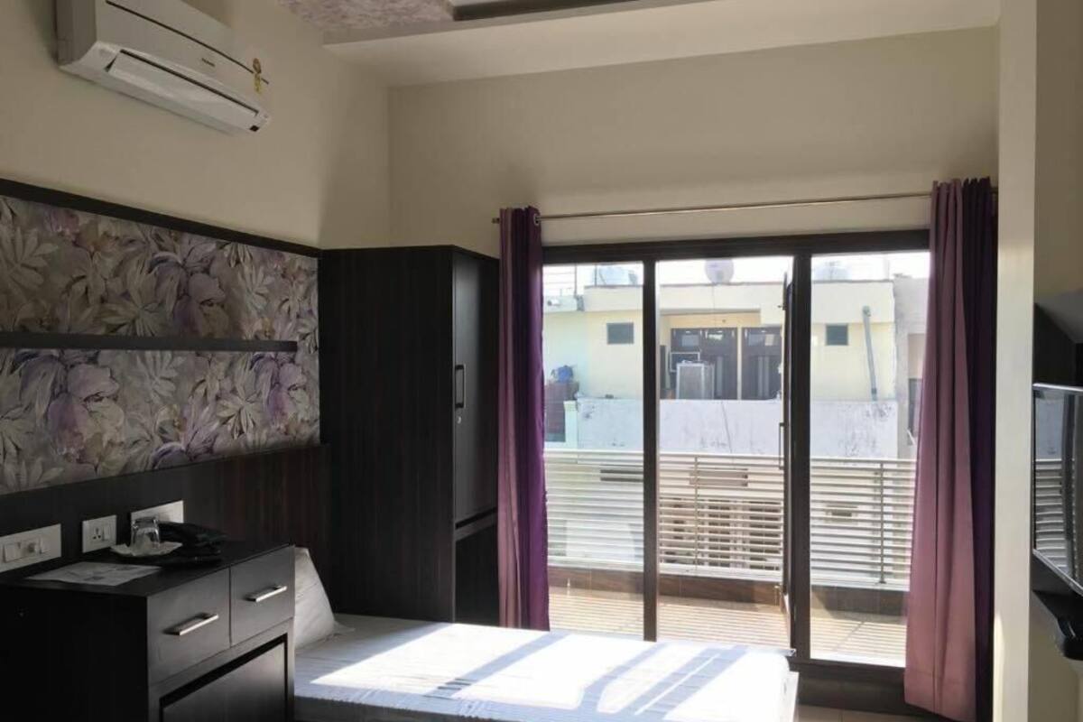 Une chambre d’hôtel équipée d’un lit, d’un bureau, d’un climatiseur, d’une fenêtre avec des rideaux et offrant une vue sur l’extérieur.