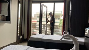 Ein Hotelzimmer mit Bett, einem fenster mit Vorhängen, einem Handtuch und einer Person, die am Fenster steht.