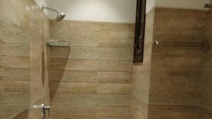 Ein kleines, schmales Badezimmer mit einem Waschbecken, einem Spiegel und einer Dusche.