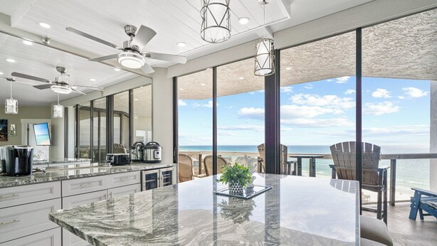 A modern kitchen with a large island, a dining area with a view of the ocean, and a balcony with outdoor seating. - Gulf-Front Luxury | Surfside 11th Floor | #1109 | 2B/2Ba (Miramar Beach)