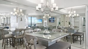 A modern dining area with a glass-top table, multiple chairs, and a chandelier. - Gulf-Front Luxury | Surfside 11th Floor | #1109 | 2B/2Ba (Miramar Beach)