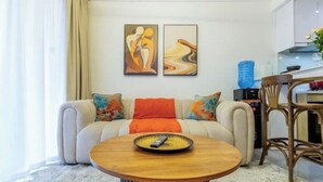 Een woonkamer met een bank, een salontafel en twee abstracte schilderijen aan de muur.