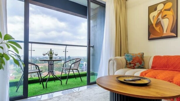 Een moderne woonkamer met balkon, een bank, een salontafel en een schilderij aan de muur.