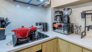 Een moderne keuken met een ingebouwde kookplaat, een koffiezetapparaat en een blender.