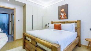 Een slaapkamer met een houten bed, witte muren en een schilderij erboven.