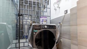 Et kompakt, moderne badeværelse med glasafskærmning, vaskemaskine og synligt toilet.