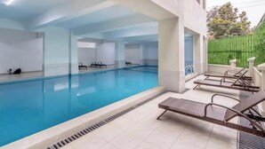 En swimmingpool med liggestole og et overdækket område.