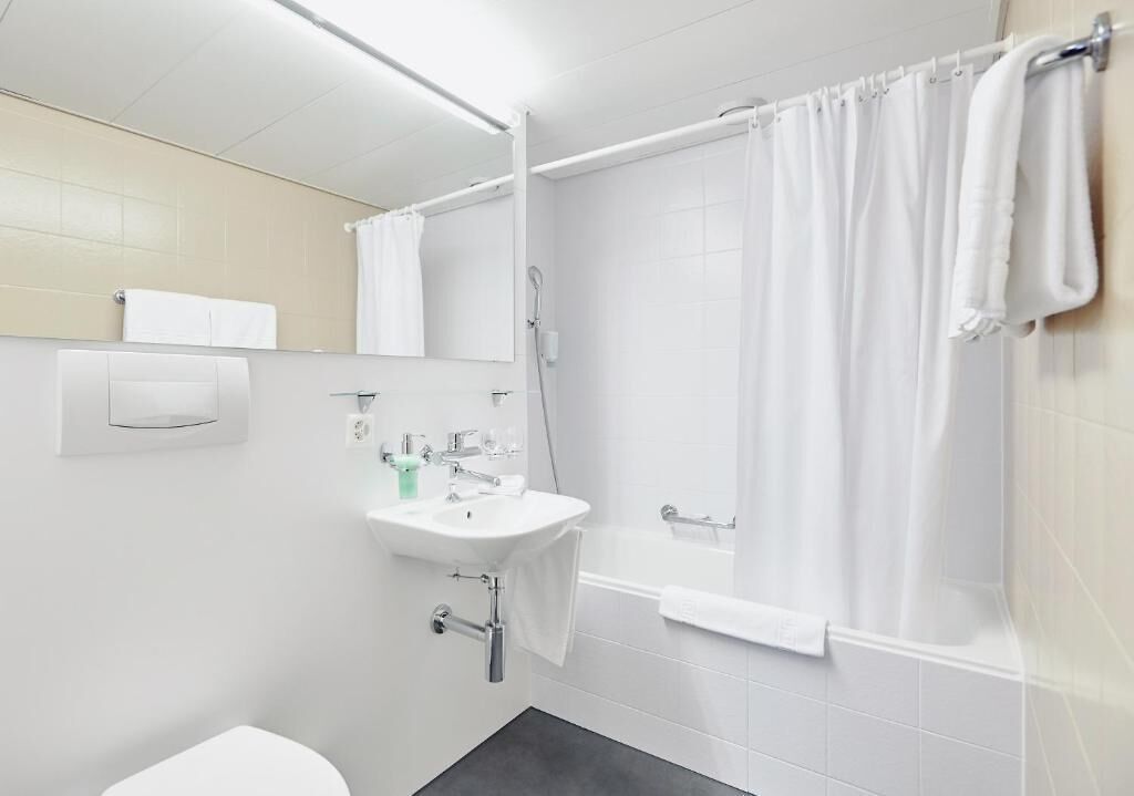 Ein modernes Badezimmer mit Waschbecken, Spiegel und Duschvorhang.