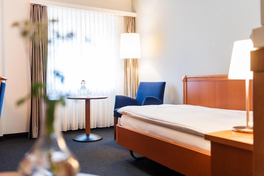 Ein Hotelzimmer mit Bett, Stuhl, kleinem Tisch und Lampe.