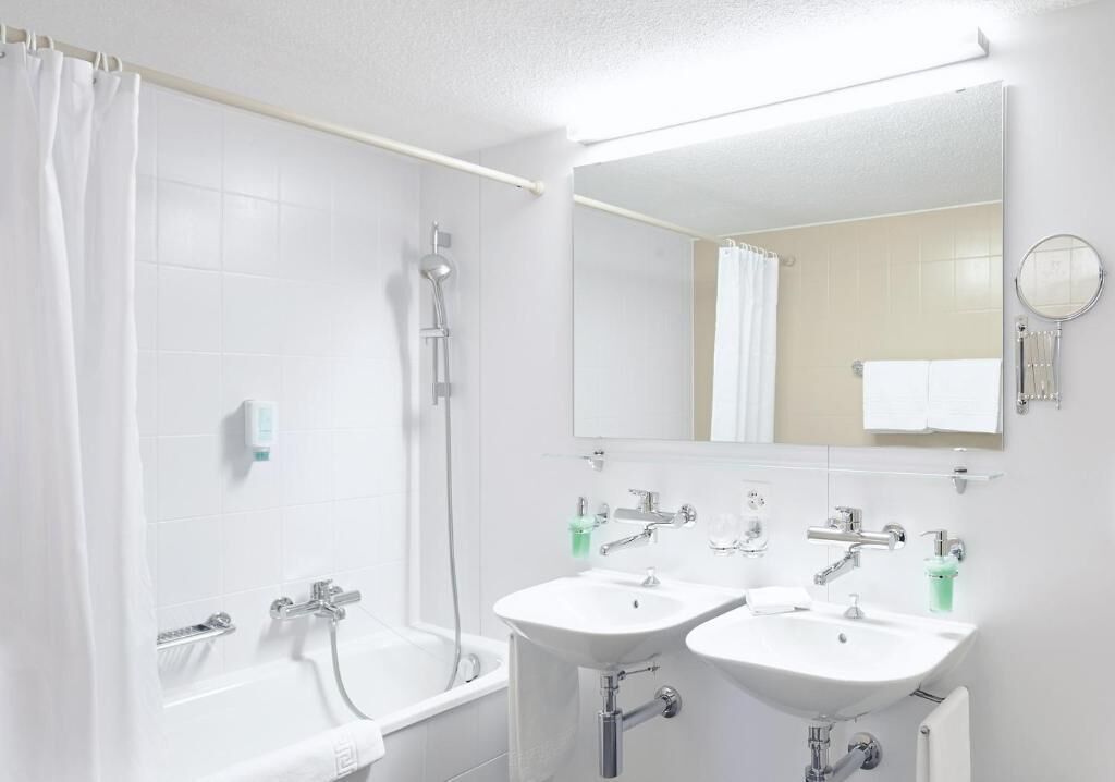 Un baño con bañera, dos lavamanos, ducha y espejo.