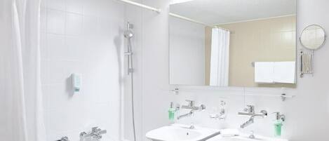 Un baño con bañera, dos lavamanos, ducha y espejo.