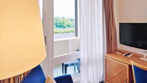 Ein Hotelzimmer mit großem Fenster, Fernseher, Schreibtisch und Stuhl.
