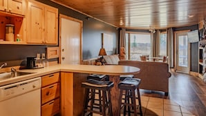Une cuisine avec des meubles de rangement en bois, un évier et un coin bar avec des tabourets.