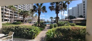 A hotel courtyard with a pool, palm trees, and a pathway leading to the pool area. - Sleeps 10 Direct Beach Heated Pool (South Padre Island)