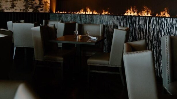 Interior de restaurante con una chimenea, asientos y una pared con textura.