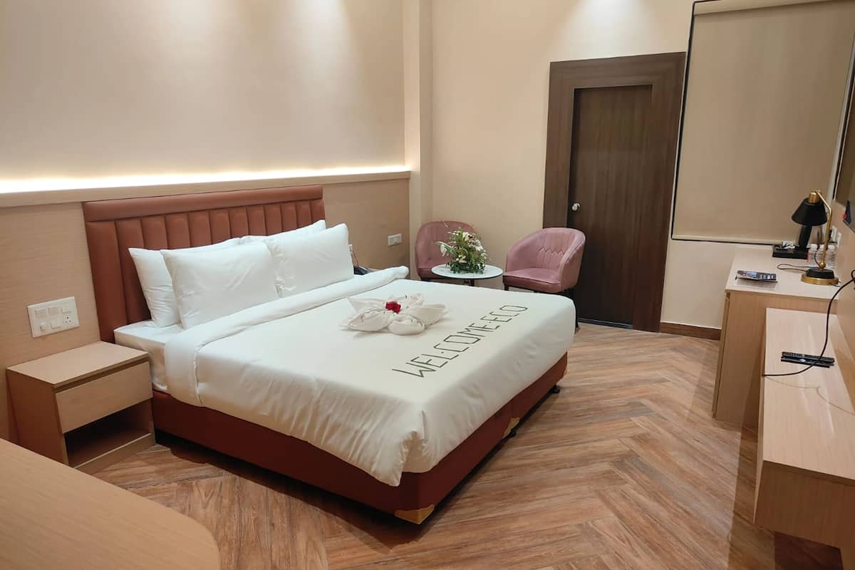 Ein Hotelzimmer mit Bett, Nachttisch, Stuhl, Schreibtisch und Spiegel.
