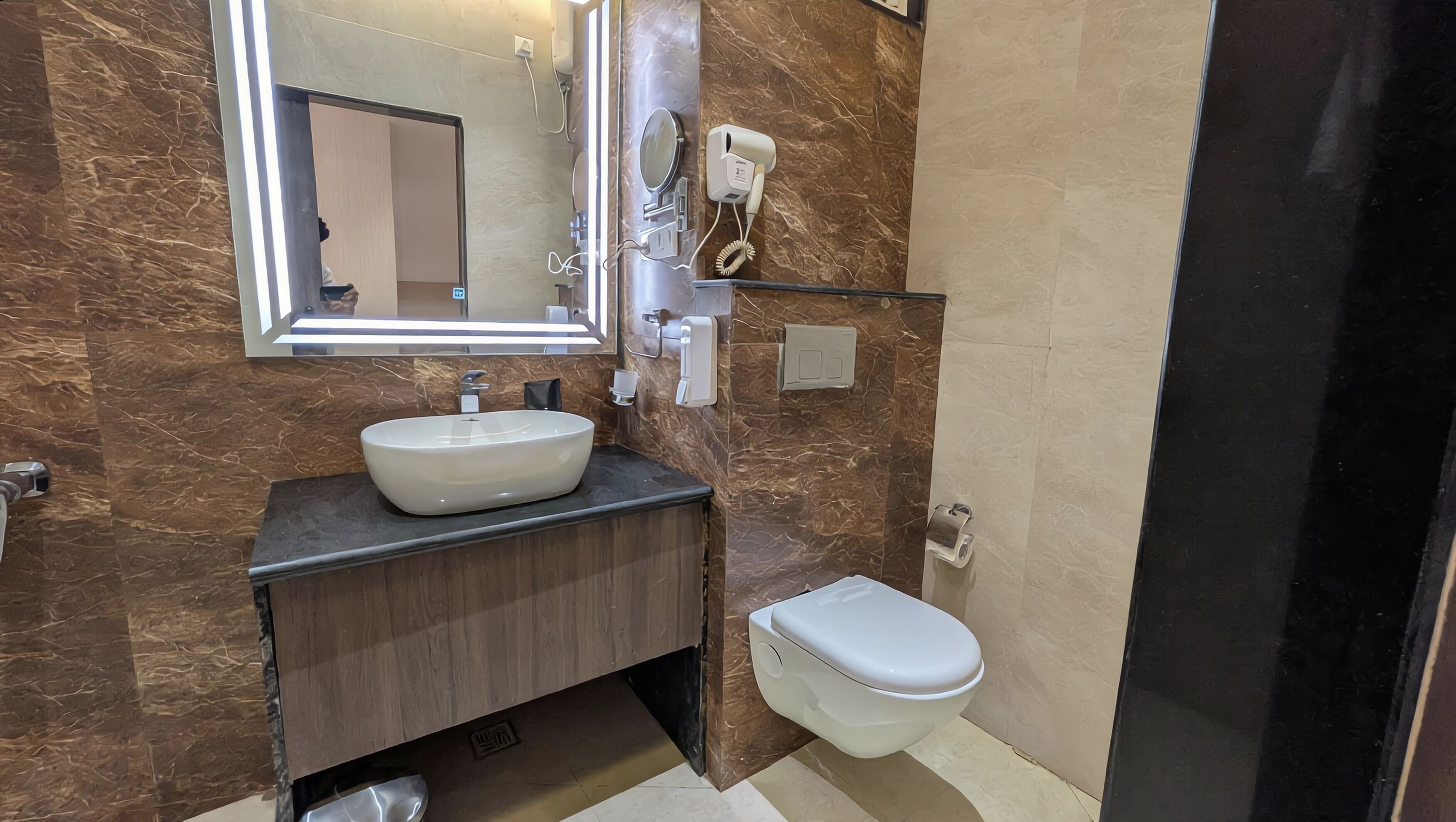 Een badkamer met een wastafel, spiegel, haardroger en toilet.