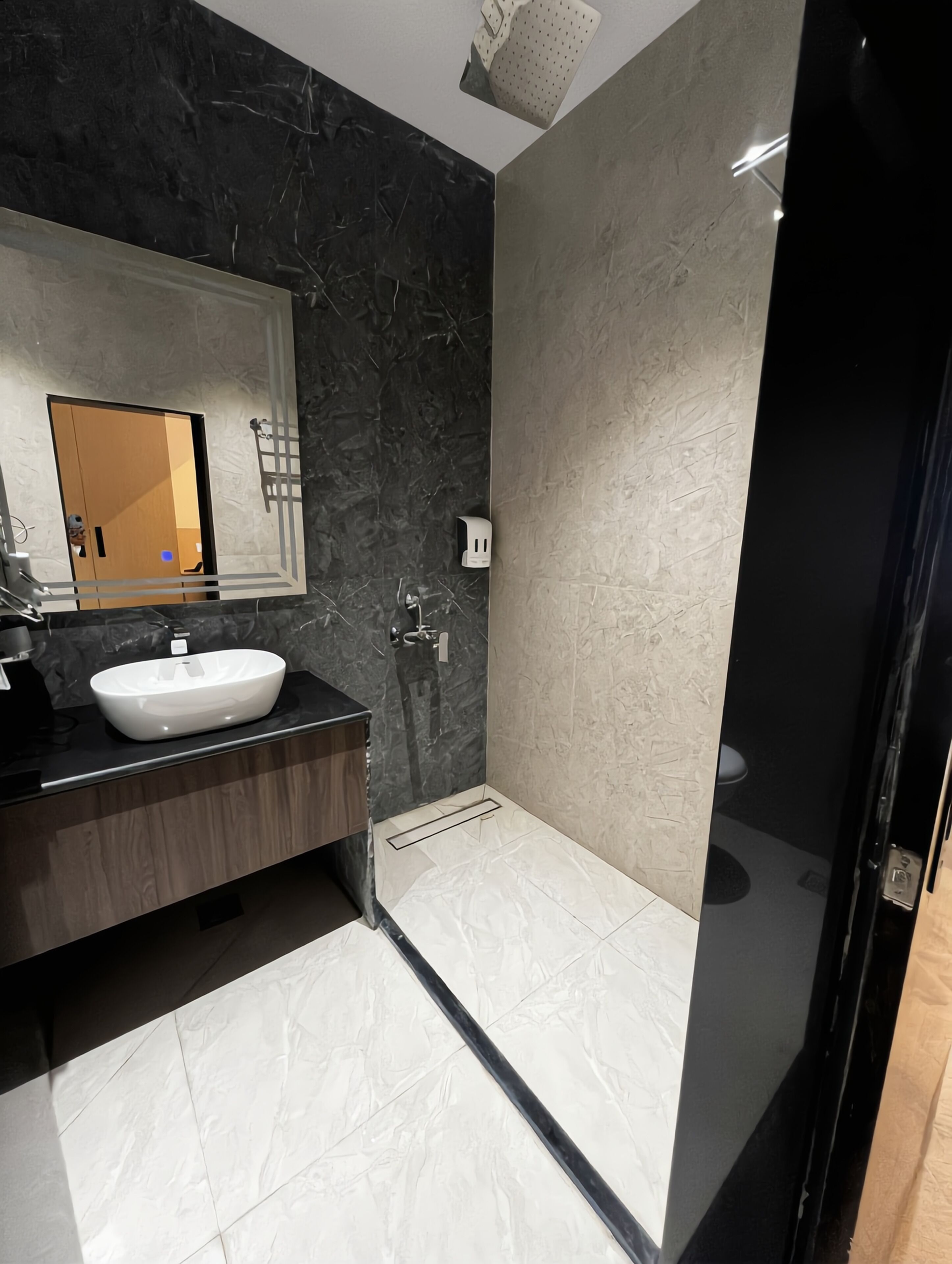 A modern bathroom with a large mirror, a white sink, and a shower area.