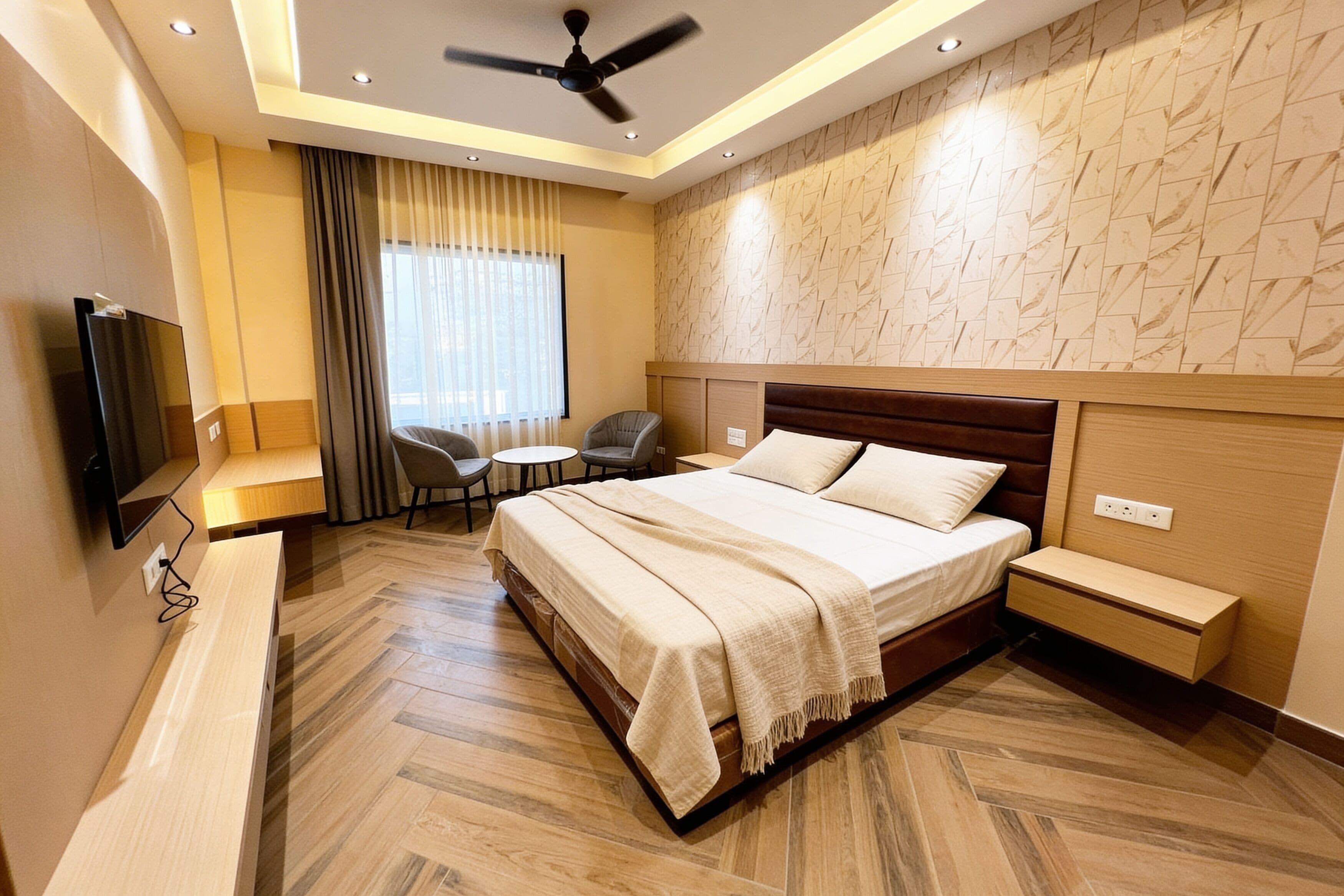 Ett modernt hotellrum med en stor säng, ett skrivbord, en stol, en TV och en takfläkt.