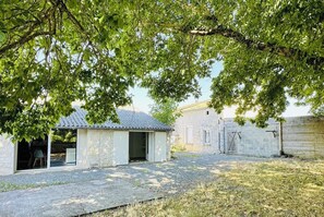 Ein rustikales Steinhaus mit Metallbedachung, einem Schotterweg und einer Rasenfläche.