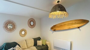 Uma sala de estar moderna com um sofá, uma mesa de centro redonda e uma decoração de prancha de surf de madeira única na parede.