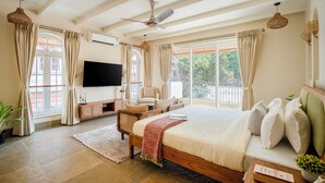 Um quarto espaçoso com uma cama grande, cabeceira de madeira, mesa de cabeceira, televisão e vista para a varanda.